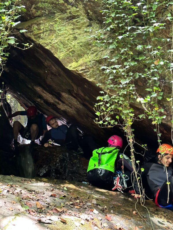 canyoning mezzanello: gruppo passa in uno stretto anfratto naturale creato da rocce e vegetazione lungo il corso del fiume mezzanello in calabria