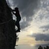 ferrata del cristo redentore di maratea: ragazzo in controluce che scala con il mare sullo sfondo